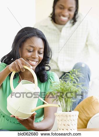Stock Image - African couple watering plant. Fotosearch