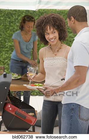 Stock Photo - African man and women barbecuing. Fotosearch