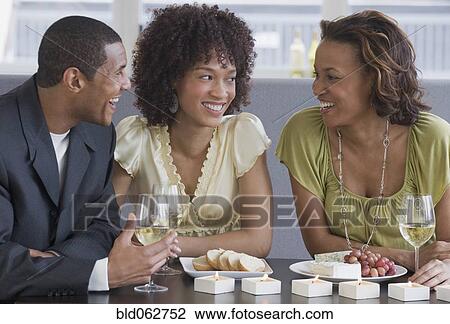Stock Image - African man and women dining in restaurant. Fotosearch