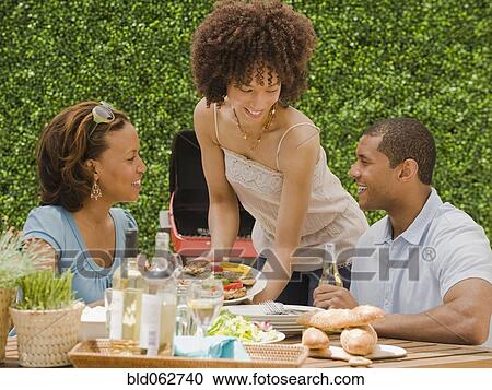 Stock Image - African man and women eating on patio. Fotosearch