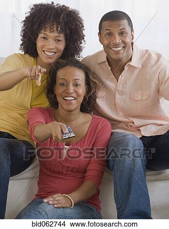Picture - African man and women watching television. Fotosearch
