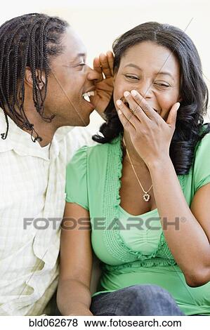 Stock Photo - African man whispering in woman's ear. Fotosearch