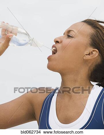 Picture - African woman drinking from water bottle. Fotosearch