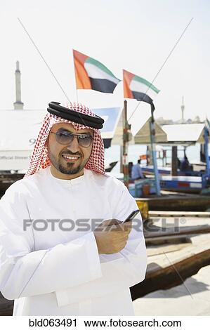 Arab man holding cell phone View Large Photo Image Stock Image - Arab man holding cell phone. Fotosearch