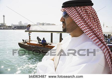 Arab man standing at waterfront View Large Photo Image Stock Photo - Arab man standing at waterfront. Fotosearch