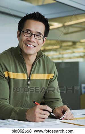 Stock Photo - Asian American businessman working in office. Fotosearch