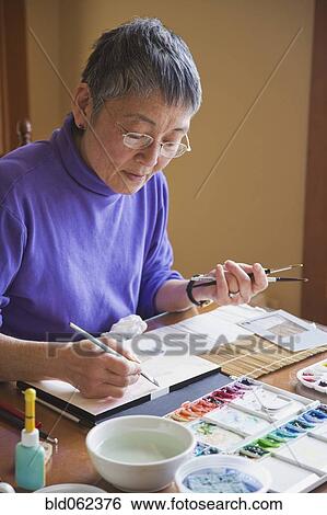 Asian woman painting at table View Large Photo Image Stock Photograph - Asian woman painting at table. Fotosearch