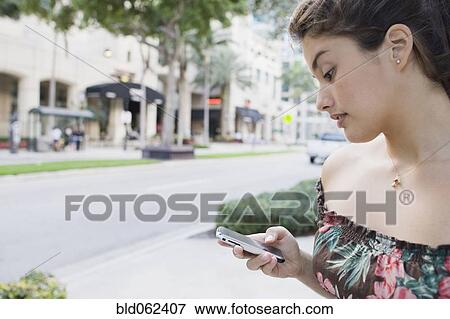 Stock Photo - Brazilian teenager text messaging on cell phone . Fotosearch