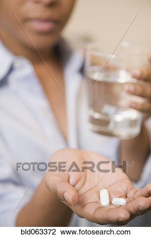 Stock Image - Close up of African woman holding pills. Fotosearch
