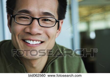 Stock Image - Close up of Asian American man wearing eyeglasses and smiling. Fotosearch