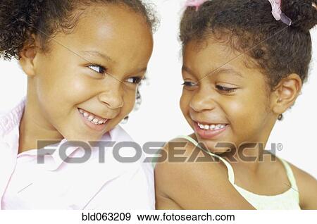 Stock Photo - Close up of multi-ethnic girls smiling at each other. Fotosearch
