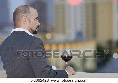 Stock Image - Cuban man with wine glass looking at view. Fotosearch