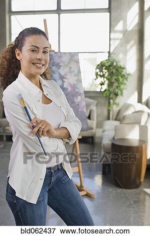 Dominican woman holding paintbrush in living room View Large Photo Image Stock Photo - Dominican woman holding paintbrush in living room. Fotosearch
