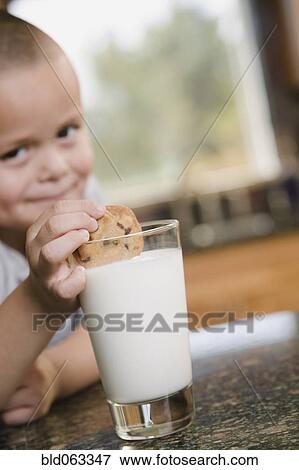 Stock Photo - Hispanic boy dunking cookie in milk. Fotosearch