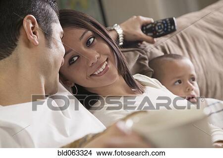 Picture - Hispanic couple and son relaxing on sofa. Fotosearch