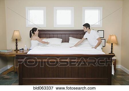 Stock Photo - Hispanic couple making bed. Fotosearch