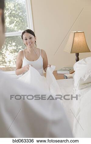 Stock Photograph - Hispanic couple making bed. Fotosearch