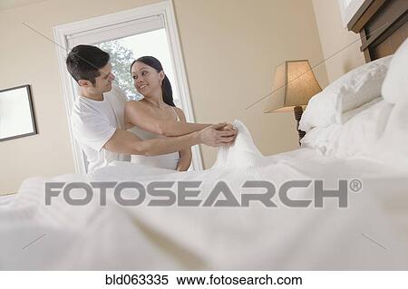 Stock Photography - Hispanic couple making bed. Fotosearch