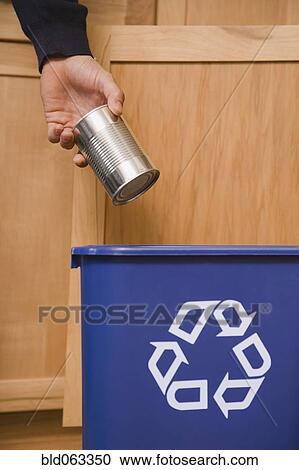 Stock Image - Hispanic man placing tin can in recycling bin. Fotosearch