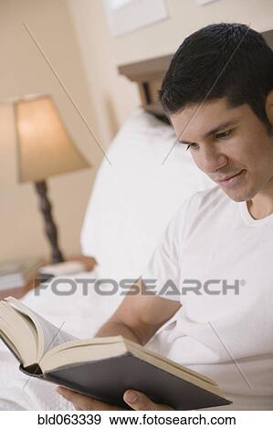 Hispanic man reading book in bed View Large Photo Image Stock Photo - Hispanic man reading book in bed. Fotosearch