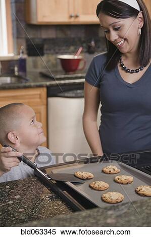 Stock Photography - Hispanic mother and son baking cookies in kitchen. Fotosearch