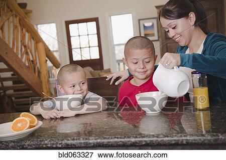 Stock Photo - Hispanic mother and sons eating breakfast. Fotosearch