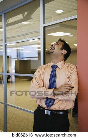 Stock Image - Indian businessman laughing in office. Fotosearch