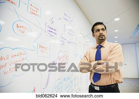 Picture - Indian businessman standing in front of whiteboard. Fotosearch