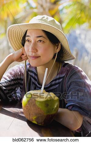 Stock Photograph - Japanese woman next to coconut. Fotosearch