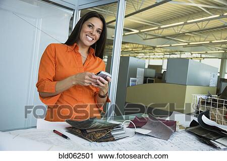 Latin American woman holding cell phone in office View Large Photo Image Stock Image - Latin American woman holding cell phone in office. Fotosearch