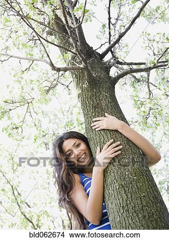 Picture - Middle Eastern woman hugging tree. Fotosearch