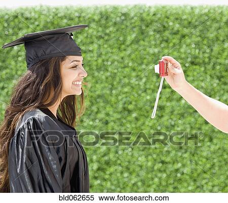 Stock Photography - Middle Eastern woman in cap and gown having photograph taken. Fotosearch