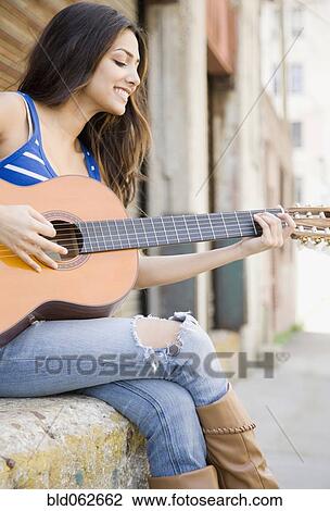 Stock Image - Middle Eastern woman playing guitar. Fotosearch