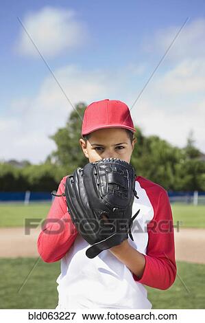 Stock Photo - Mixed race boy in baseball uniform holding glove and concentrating. Fotosearch