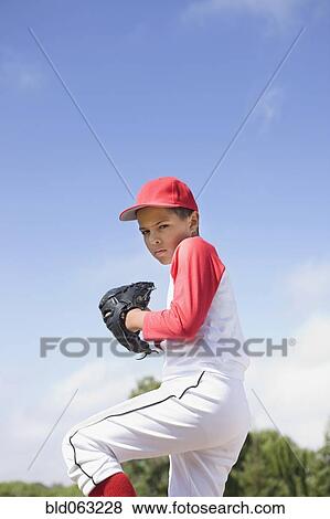 Stock Photo - Mixed race boy in baseball uniform pitching in game. Fotosearch