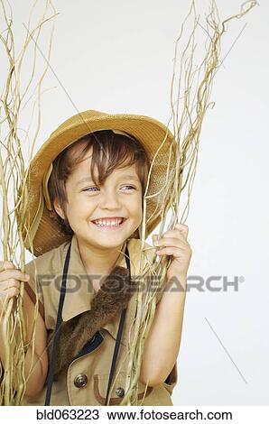 Stock Image - Mixed race boy in safari outfit holding branches. Fotosearch