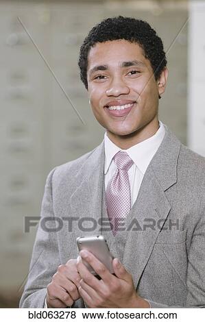 Mixed race businessman holding cell phone View Large Photo Image Stock Photo - Mixed race businessman holding cell phone. Fotosearch