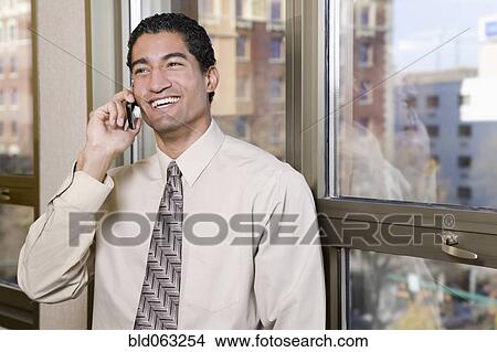 Picture - Mixed race businessman talking on cell phone. Fotosearch