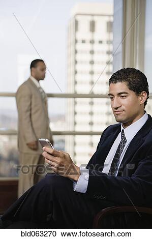 Stock Image - Mixed race businessman using cell phone. Fotosearch