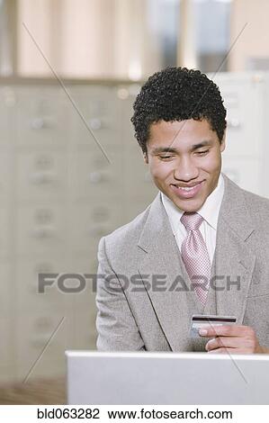 Mixed race businessman with laptop holding credit card View Large Photo Image Stock Image - Mixed race businessman with laptop holding credit card. Fotosearch