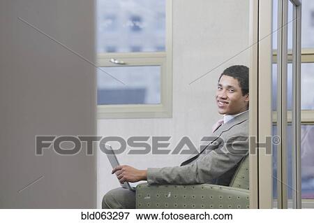 Stock Photo - Mixed race businessman working on laptop in office. Fotosearch