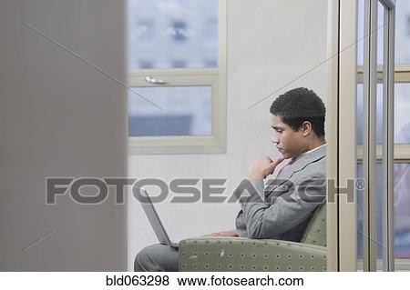 Stock Photo - Mixed race businessman working on laptop in office. Fotosearch