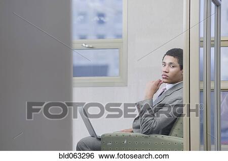 Stock Photograph - Mixed race businessman working on laptop and looking serious. Fotosearch