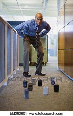Mixed race man staring at cell phones on office floor View Large Photo Image Stock Image - Mixed race man staring at cell phones on office floor. Fotosearch