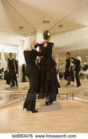 Stock Photograph - Mixed race woman having flamenco dress fitted by tailor. Fotosearch