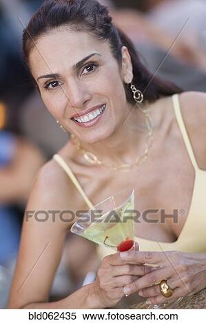 Stock Photography - Mixed race woman holding martini glass. Fotosearch