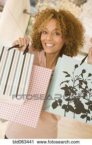 Stock Image - Mixed race woman holding shopping bags. Fotosearch