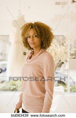 Stock Photo - Mixed race woman in clothing shop. Fotosearch