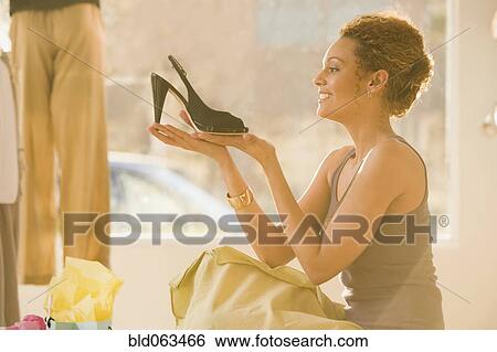 Stock Photograph - Mixed race woman shoe shopping. Fotosearch