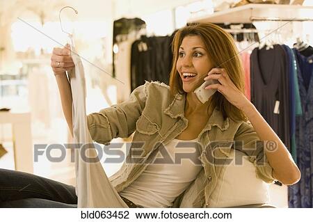 Mixed race woman shopping while talking on cell phone View Large Photo Image Stock Image - Mixed race woman shopping while talking on cell phone. Fotosearch